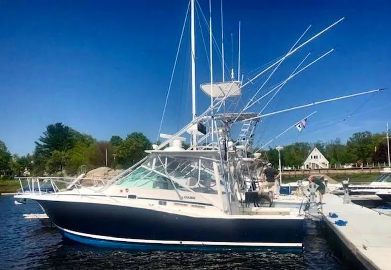 Wanda Lee Yacht Photos Pics 1999 Cabo 31 Express boat docked, featuring fishing rods and a clear blue sky.
