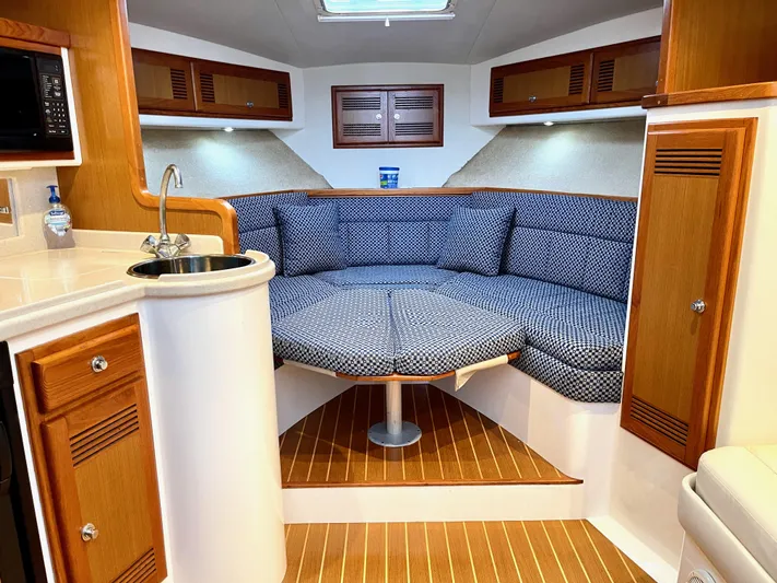 Wanda Lee Yacht Photos Pics 1999 Cabo 31 Express interior with cozy seating, wooden cabinets, and compact kitchenette.