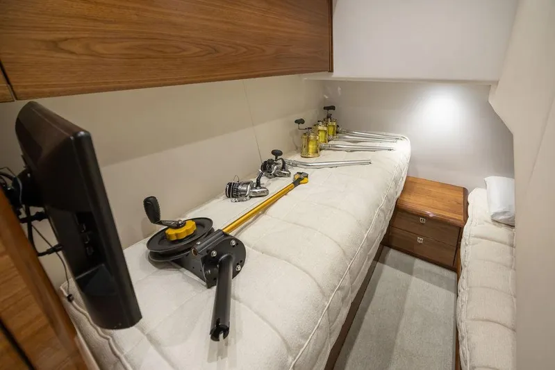 Seven Seas Yacht Photos Pics 2024 Viking 58 Convertible cabin with fishing gear on bed, wooden cabinets, and soft lighting.