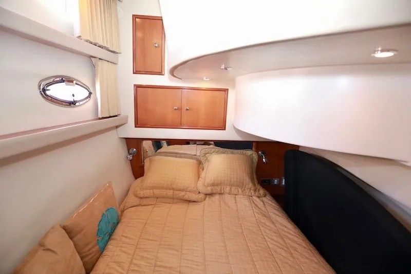 Four Us Yacht Photos Pics Interior cabin of 2006 Carver 42 Super Sport yacht with cozy bedding and wooden cabinets.