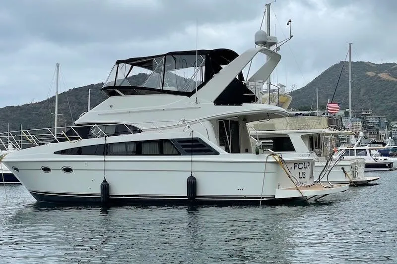 Four Us Yacht Photos Pics 2006 Carver 42 Super Sport yacht docked in a marina with mountainous backdrop.