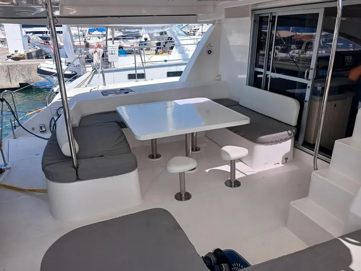 Andiamo IV Yacht Photos Pics Spacious seating area on a 2018 Leopard 48 yacht, featuring a modern table and cushioned benches.