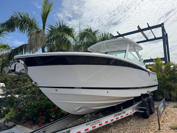  Yacht Photos Pics 2026 Blackfin 302 DC boat on trailer, surrounded by palm trees and a cloudy sky.