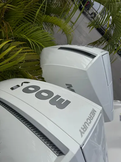  Yacht Photos Pics Twin Mercury outboard engines on a 2026 Blackfin 302 DC boat, surrounded by greenery.