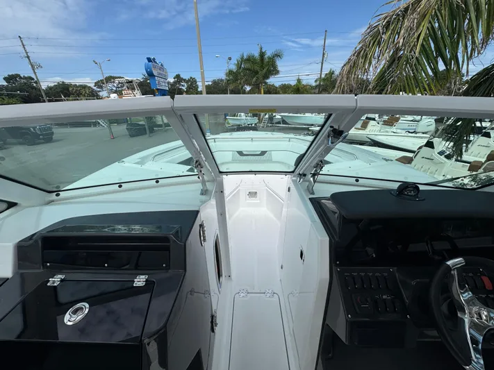  Yacht Photos Pics 2026 Blackfin 302 DC boat interior with steering wheel and dashboard, under clear blue sky.