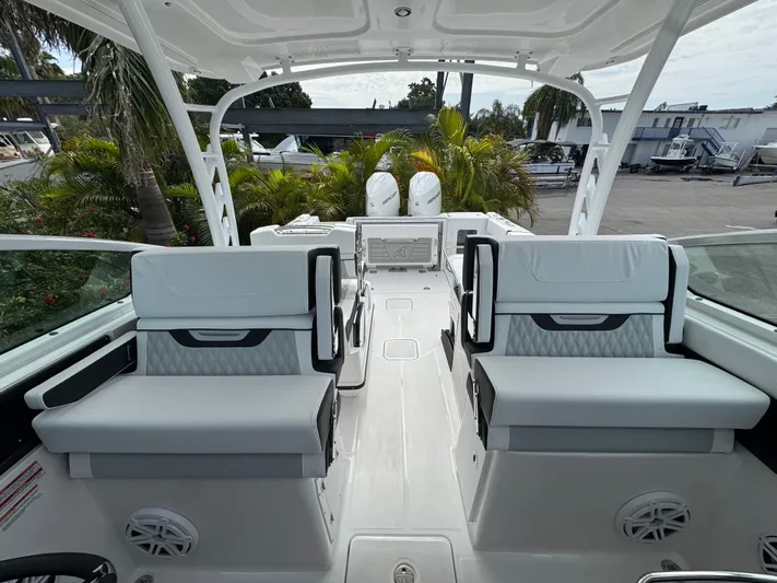  Yacht Photos Pics 2026 Blackfin 302 DC boat interior with modern seating and dual engines, surrounded by lush greenery.