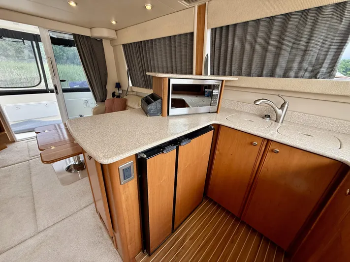  Yacht Photos Pics 2004 Meridian 381 Sedan interior with kitchenette, featuring wood cabinets, sink, and microwave.