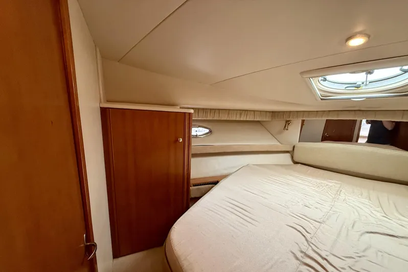  Yacht Photos Pics 2004 Meridian 381 Sedan cabin interior with bed, wooden cabinet, and porthole window.