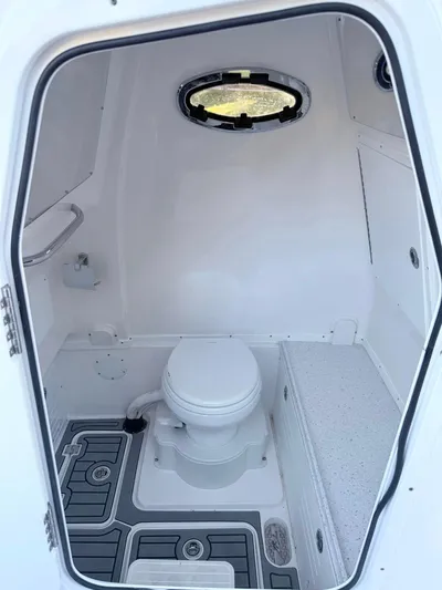  Yacht Photos Pics 2025 Tidewater 3100 Carolina Bay boat interior with compact marine toilet and porthole.