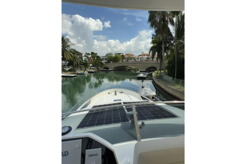 Waxing Gibbous Yacht Photos Pics 2024 Greenline 48 Fly yacht cruising through a scenic canal with palm trees.
