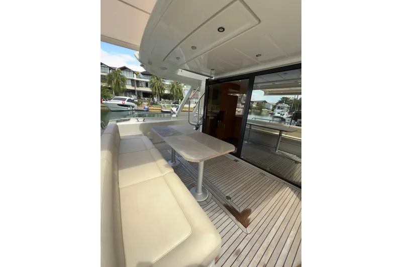 Waxing Gibbous Yacht Photos Pics 2024 Greenline 48 Fly yacht deck with seating and table, docked near waterfront homes.