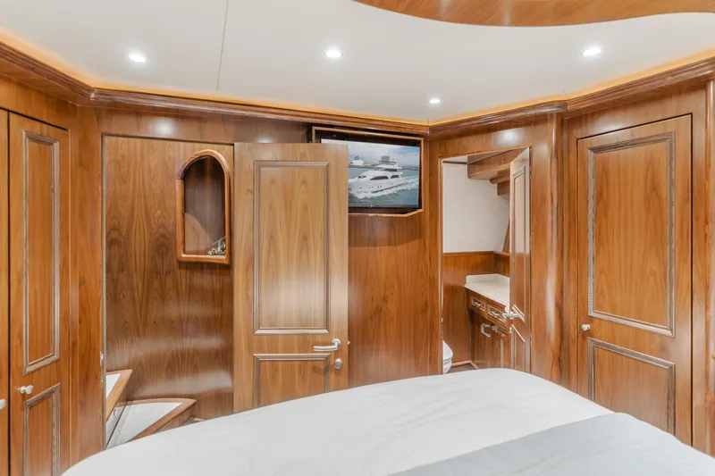 White Lotus Yacht Photos Pics Luxurious wood-paneled interior of 2011 President Sterling Tri-Deck yacht cabin with TV and storage.