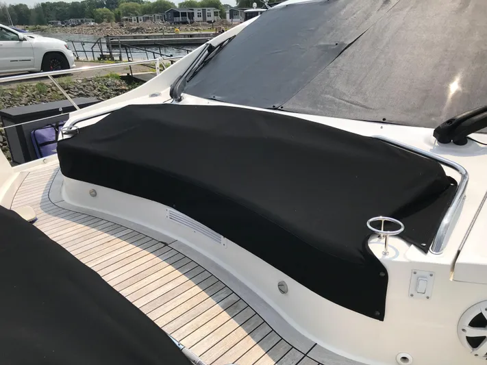 Forevermore Yacht Photos Pics 2016 Sea Ray L590 Fly yacht with black cover on deck, docked near shoreline.