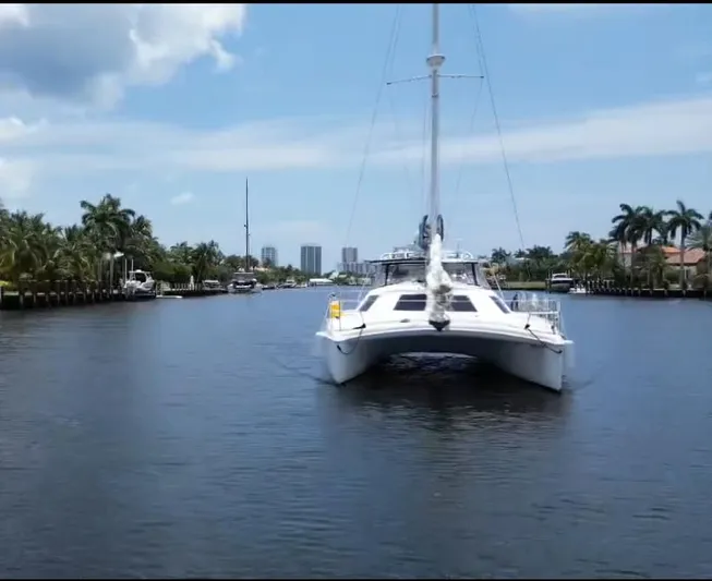 Making Memorie's Yacht Photos Pics 1999 Manta 40 catamaran sailing in a calm, palm-lined waterway under a clear sky.