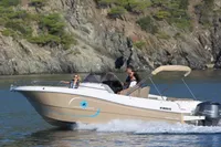 2023 Pacific Craft 750 Open boat cruising near rocky shoreline.