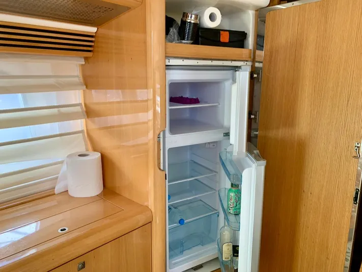  Yacht Photos Pics Open fridge in Absolute 45 yacht kitchen, showcasing wooden cabinetry and minimal contents.