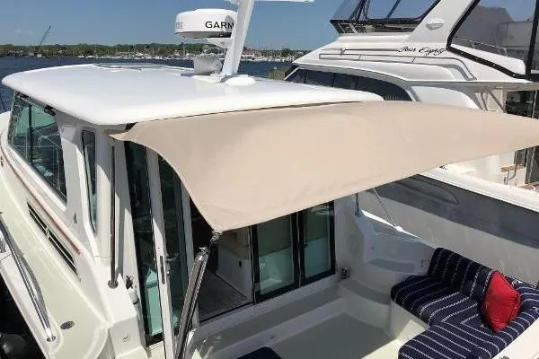  Yacht Photos Pics 2018 Back Cove Downeast 37 boat with sunshade and seating area, docked beside another vessel.