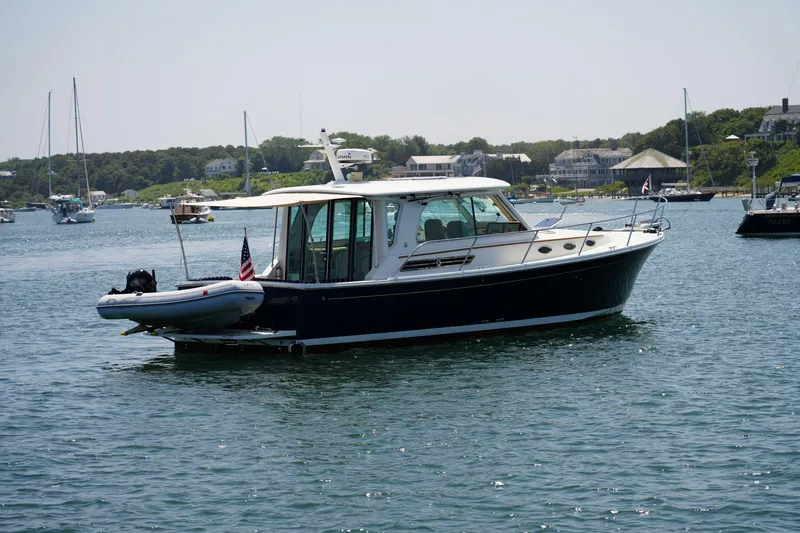  Yacht Photos Pics 2018 Back Cove Downeast 37 boat on calm water, with scenic coastal background.