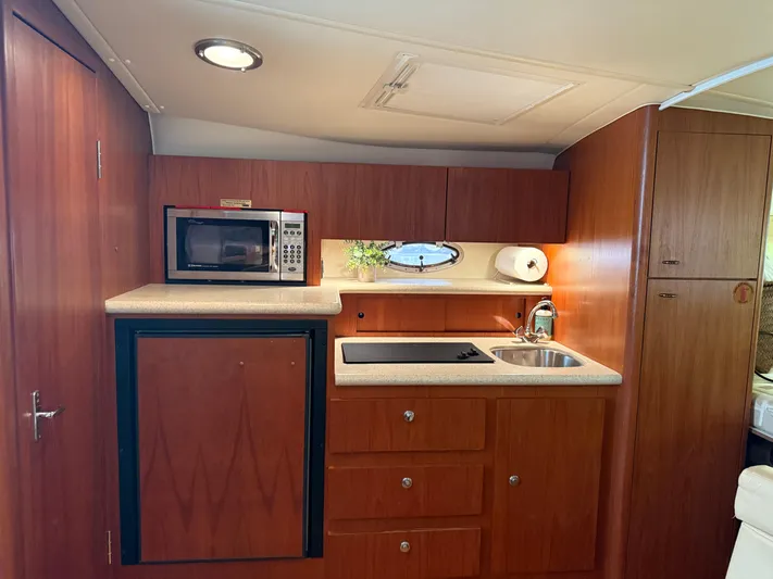Awol Yacht Photos Pics 2003 Tiara Yachts 3100 Open LE interior kitchen with microwave, sink, and wooden cabinetry.