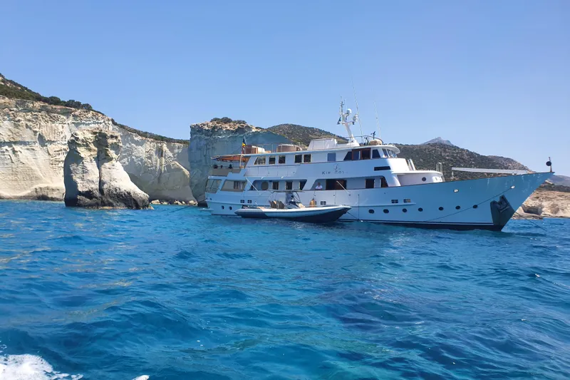 Le Kir Royal Yacht Photos Pics 1966 Van den Akker Displacement yacht near rocky cliffs in clear blue water.