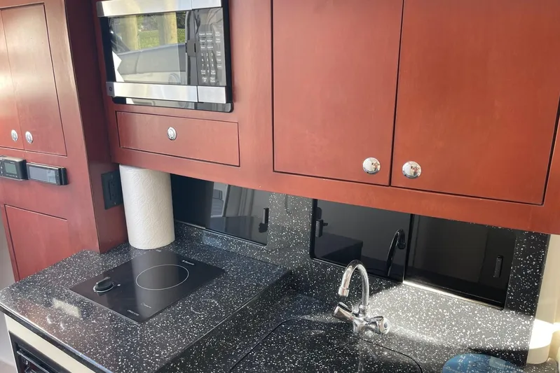 Roweboat Yacht Photos Pics Modern yacht kitchen with sleek black countertop, microwave, and wooden cabinets in 2010 Concept 4400 Sport Yacht.