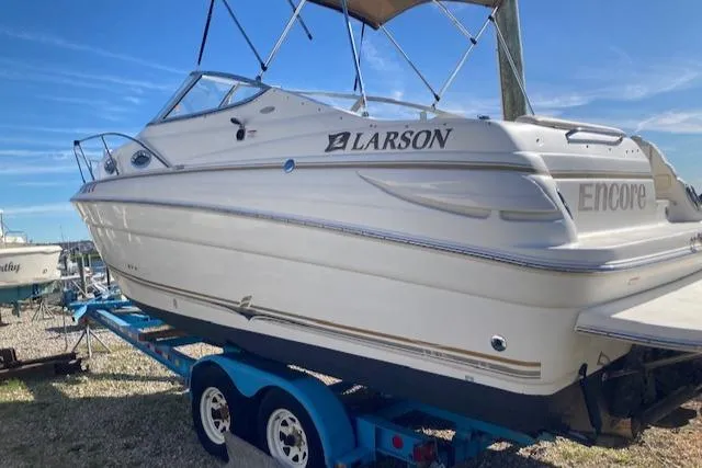 2004 Larson 240 Cabrio boat on trailer, side view, sunny day.