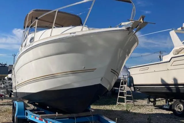 2004 Larson 240 Cabrio boat on trailer under clear blue sky.