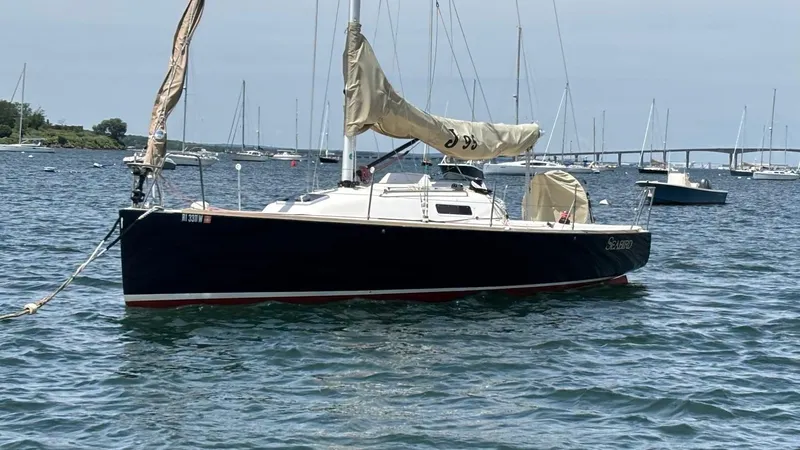 Seabird Yacht Photos Pics 2012 J Boats J/95 sailboat anchored in a calm harbor with distant bridge.