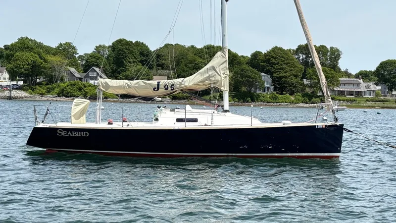 Seabird Yacht Photos Pics 2012 J Boats J/95 sailboat on calm water near a coastal neighborhood.