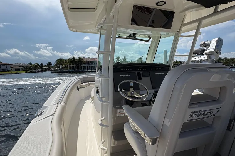  Yacht Photos Pics 2017 Boston Whaler 330 Outrage boat interior with steering console and waterfront view.