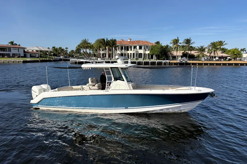  Yacht Photos Pics 2017 Boston Whaler 330 Outrage boat on water, with luxury homes and palm trees in background.
