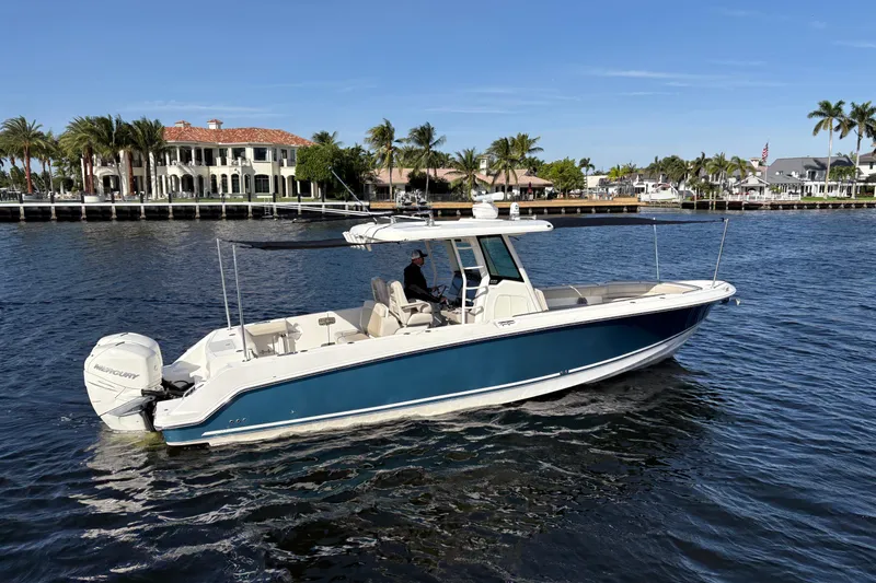 Yacht Photos Pics 2017 Boston Whaler 330 Outrage boat cruising on a sunny waterfront with palm trees.