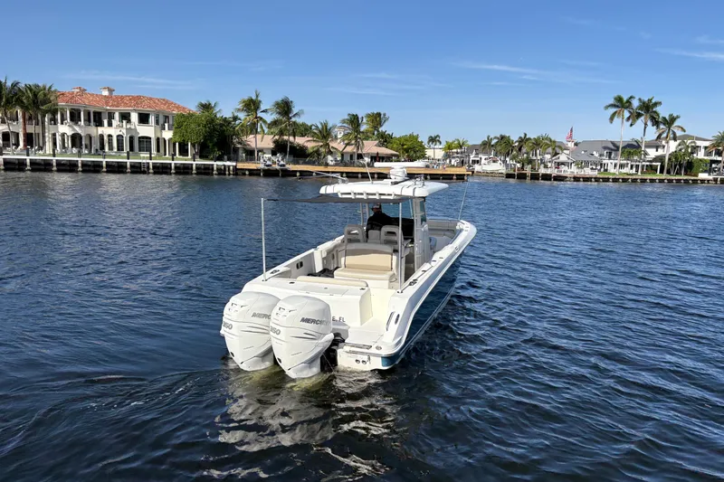  Yacht Photos Pics 2017 Boston Whaler 330 Outrage boat cruising on a sunny waterfront with luxury homes.