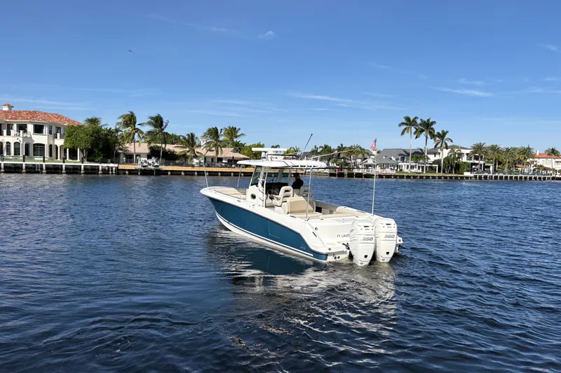  Yacht Photos Pics 2017 Boston Whaler 330 Outrage boat cruising on a sunny waterfront with palm trees.