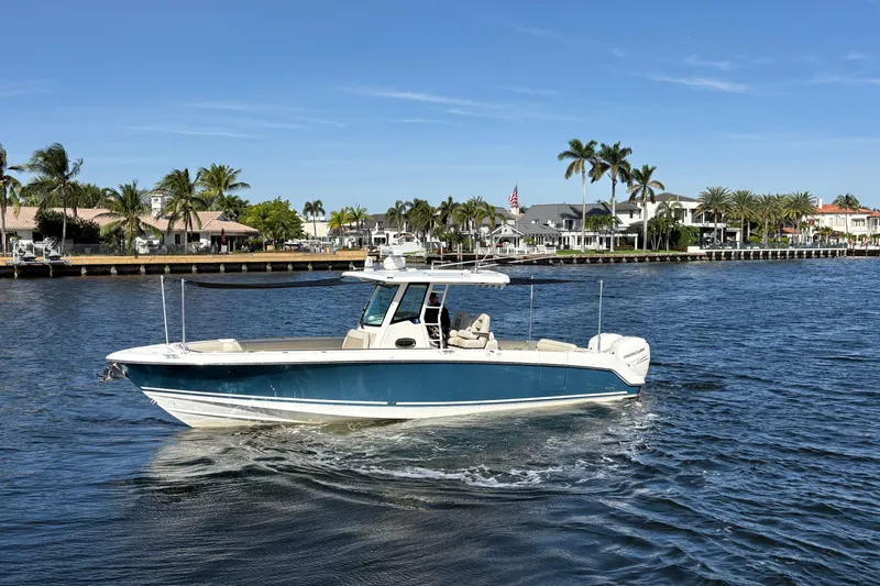  Yacht Photos Pics 2017 Boston Whaler 330 Outrage boat cruising on a sunny waterfront with palm trees.