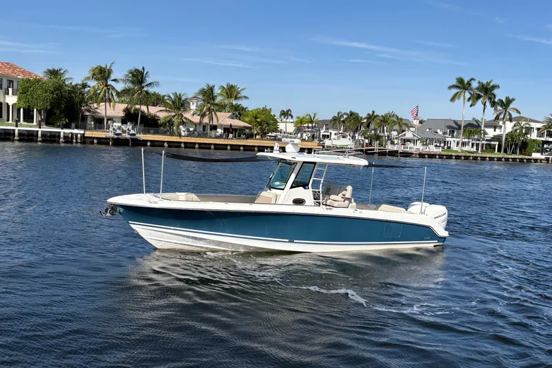  Yacht Photos Pics 2017 Boston Whaler 330 Outrage boat cruising on a sunny waterfront with palm trees.