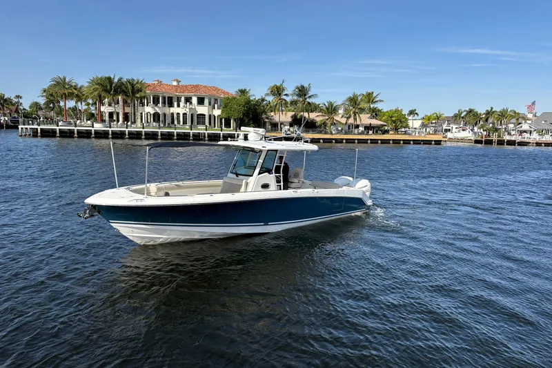  Yacht Photos Pics 2017 Boston Whaler 330 Outrage boat cruising on a sunny waterfront with palm trees.