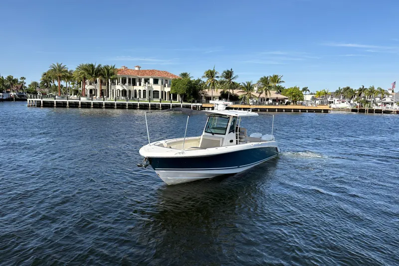  Yacht Photos Pics 2017 Boston Whaler 330 Outrage cruising on a sunny waterfront with palm trees and luxury homes.
