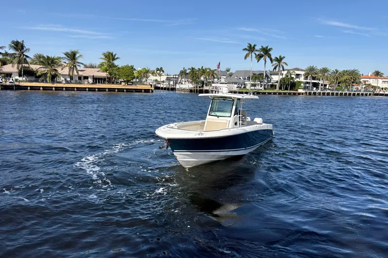  Yacht Photos Pics 2017 Boston Whaler 330 Outrage boat cruising on a sunny waterfront with palm trees.