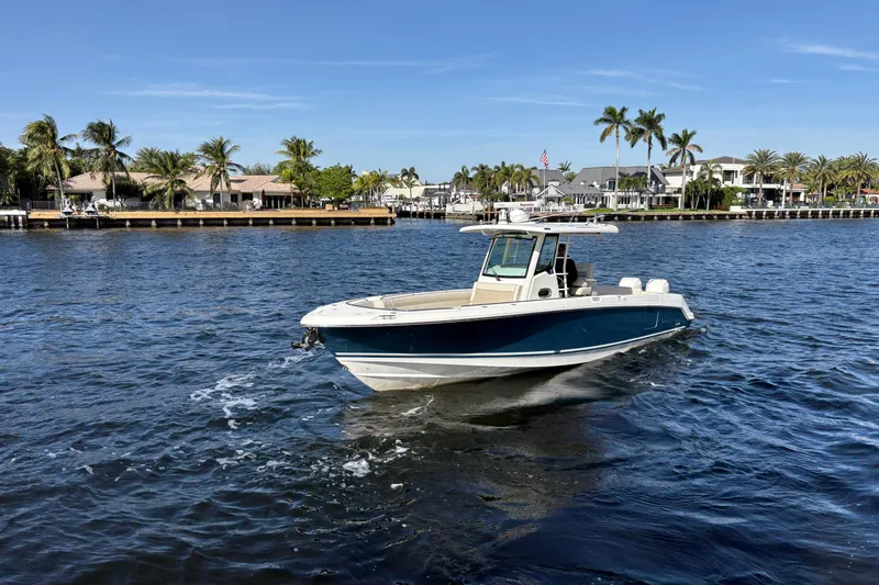  Yacht Photos Pics 2017 Boston Whaler 330 Outrage cruising on a sunny waterfront with palm trees.