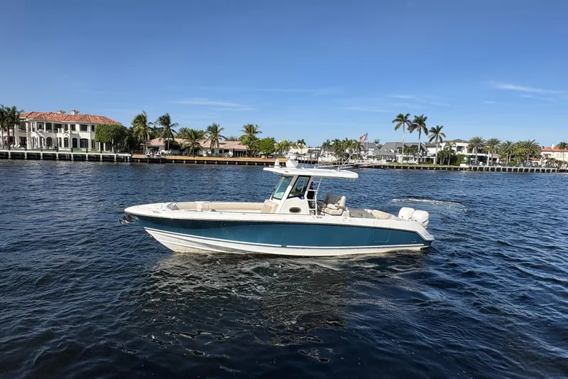  Yacht Photos Pics 2017 Boston Whaler 330 Outrage boat cruising on a sunny waterfront with palm trees.