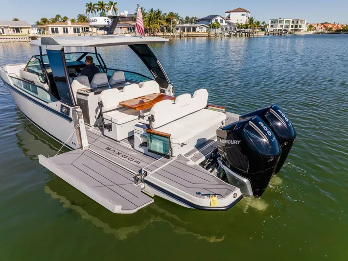  Yacht Photos Pics 2024 Saxdor 320 GTO boat with dual Mercury engines on a calm waterfront.