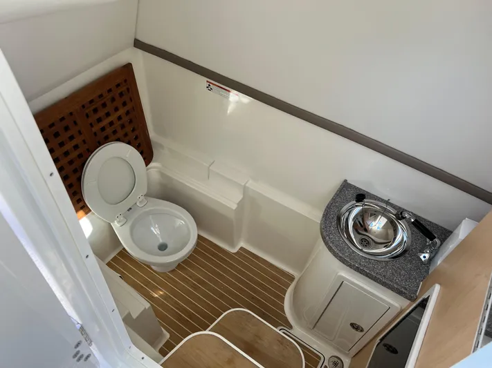  Yacht Photos Pics 2019 World Cat 320 DC boat bathroom with toilet, sink, and wooden flooring.
