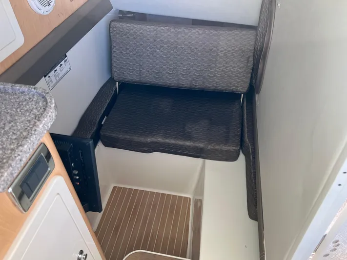  Yacht Photos Pics 2019 World Cat 320 DC interior seating area with cushioned seat and wooden flooring.