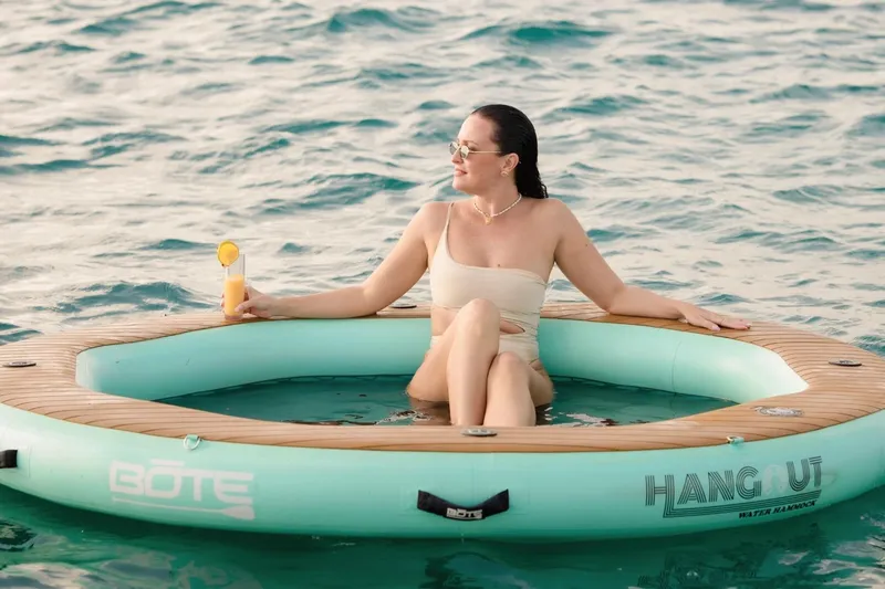 Beyond Yacht Photos Pics Woman relaxing on inflatable water hammock with drink, near Fountaine Pajot Aura 51, 2022.