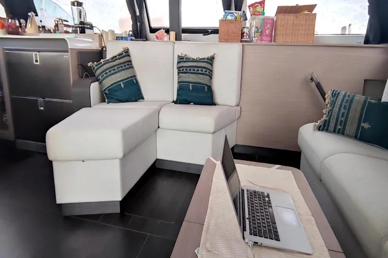 Beyond Yacht Photos Pics Luxurious interior of 2022 Fountaine Pajot Aura 51 catamaran with cozy seating and laptop.