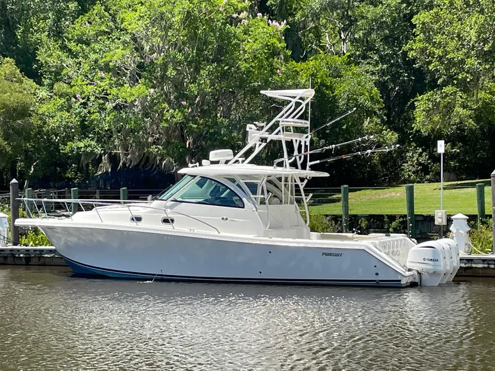  Yacht Photos Pics 2021 Pursuit OS 385 Offshore boat docked by lush greenery.