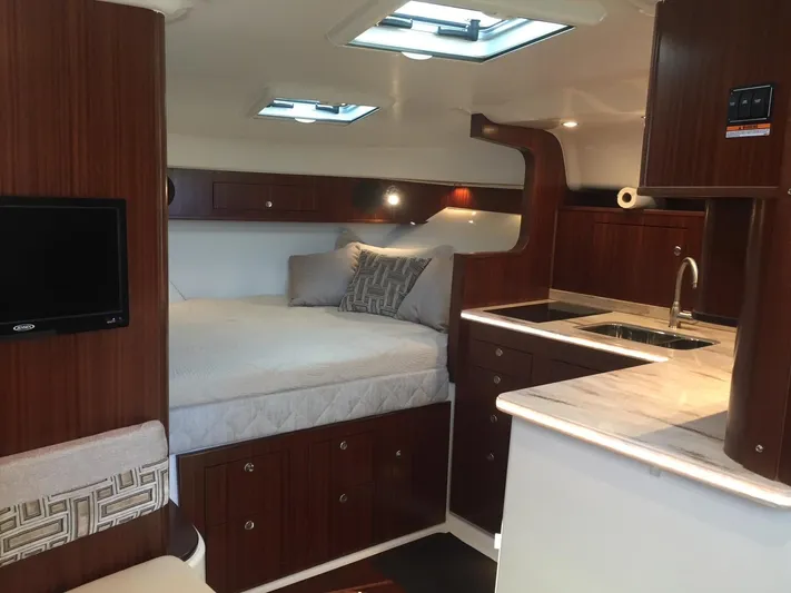  Yacht Photos Pics Luxurious interior of 2021 Pursuit OS 385 Offshore boat with bed and kitchenette.