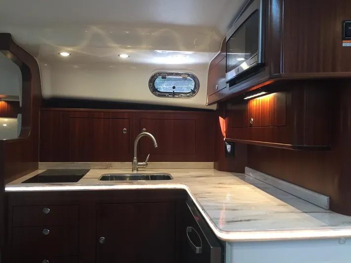  Yacht Photos Pics Luxurious 2021 Pursuit OS 385 Offshore yacht kitchen with wood cabinetry and modern appliances.