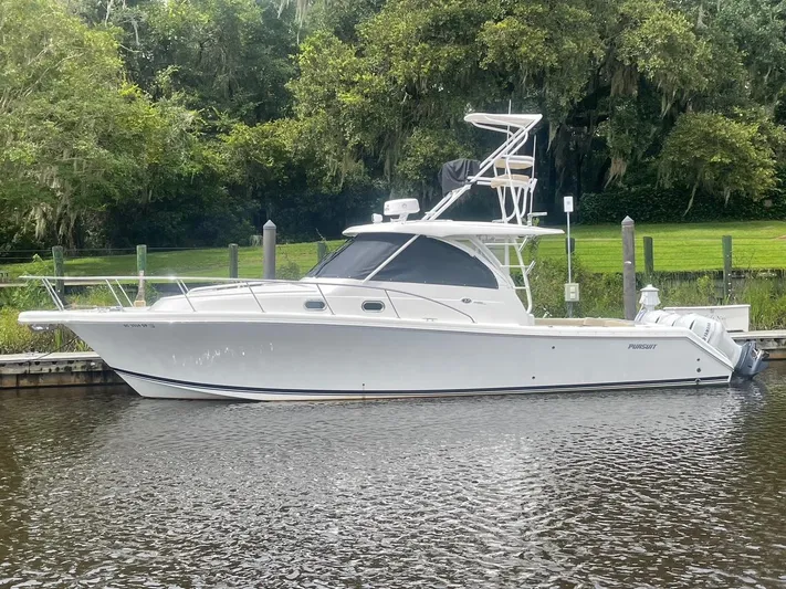  Yacht Photos Pics 2021 Pursuit OS 385 Offshore boat docked by lush greenery.